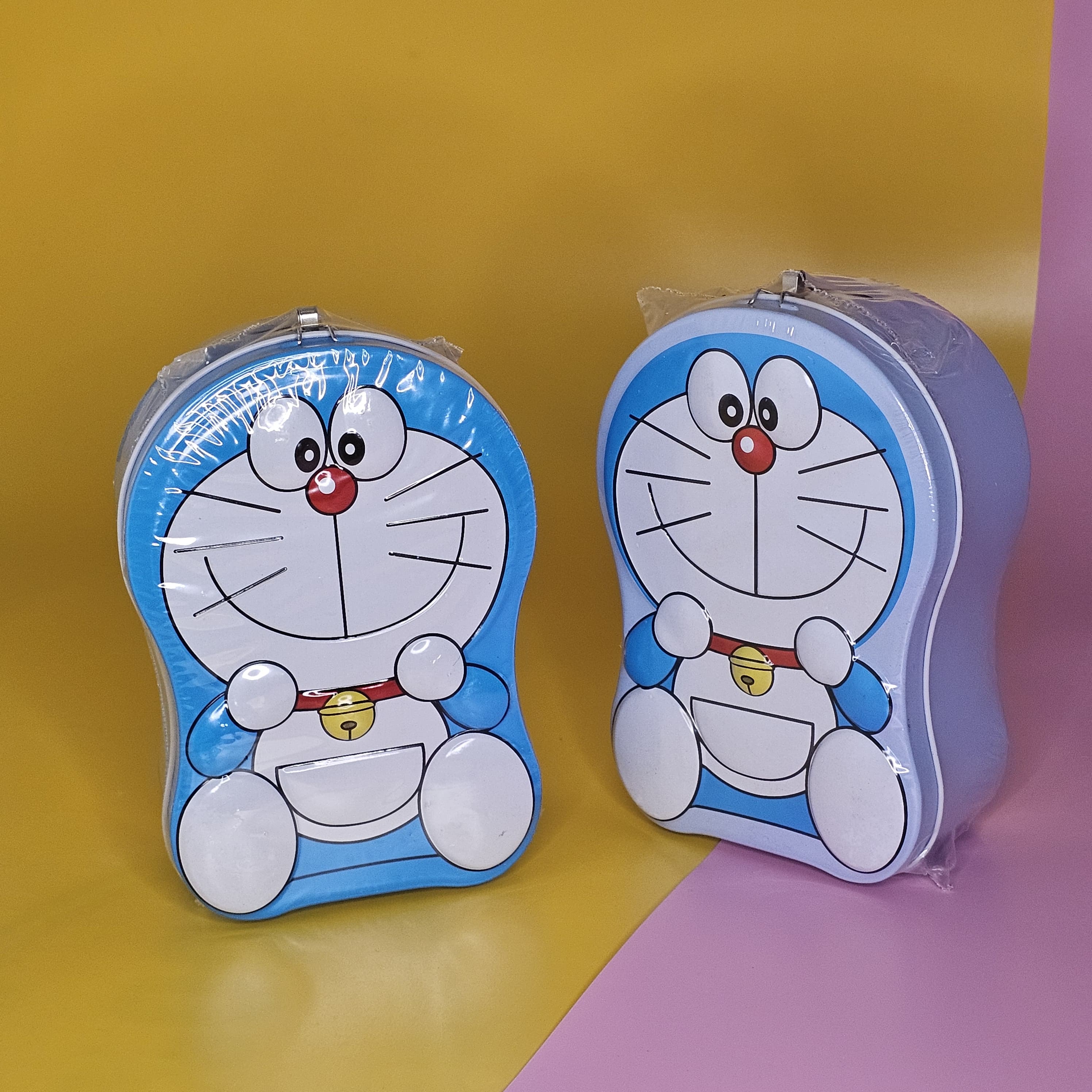 Blue and white Doraemon-shaped metal money box (piggy bank) with a top slot for coins, featuring a lock and key for secure saving. Ideal gift for kids from uSmile.toys." www.usmile.toys